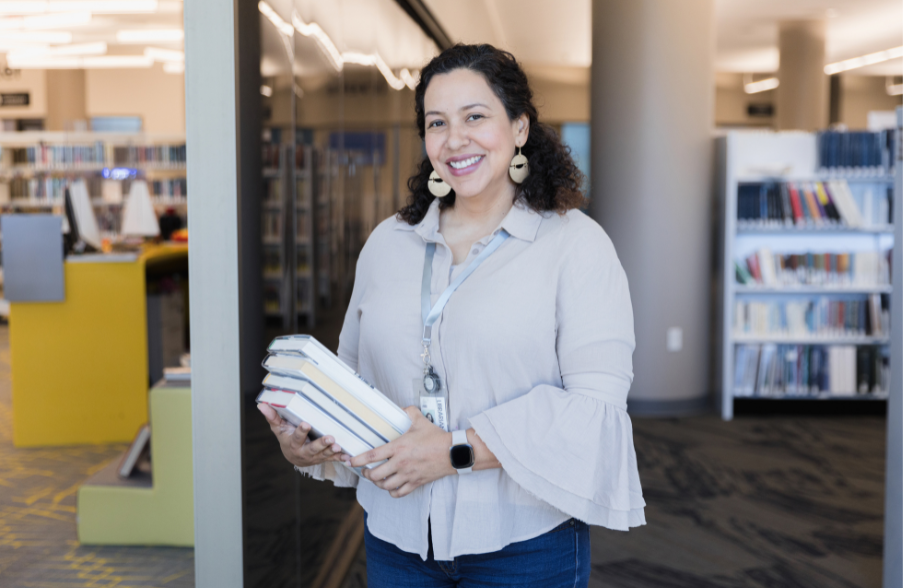 woman smiling in front of library holding books