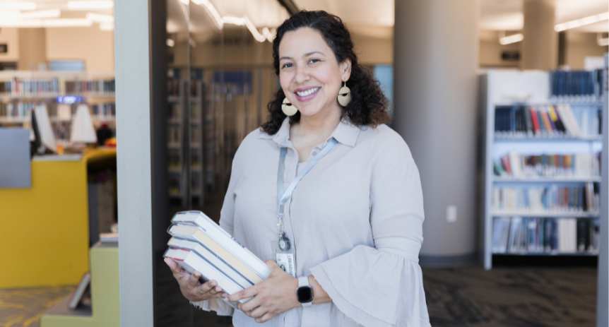 woman smiling in front of library holding books