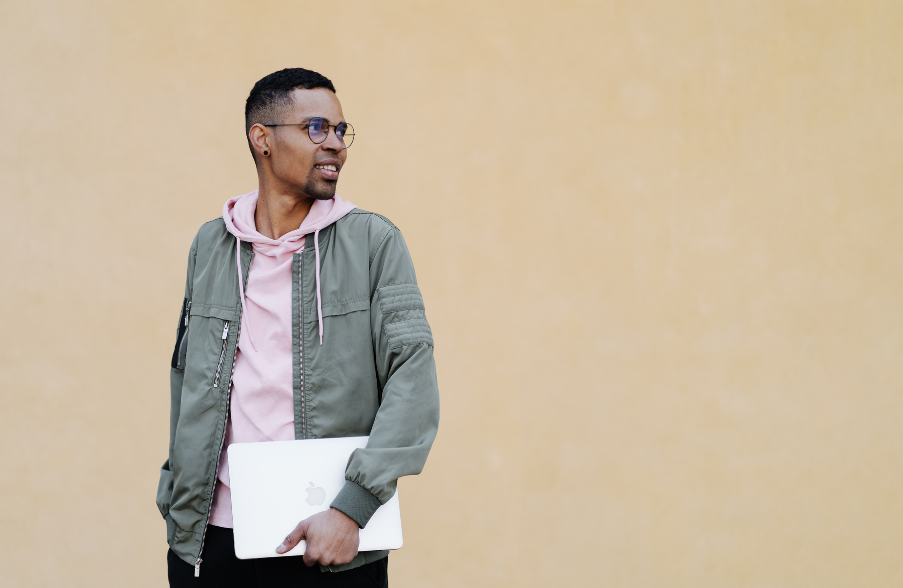 man in front of beige background holding books