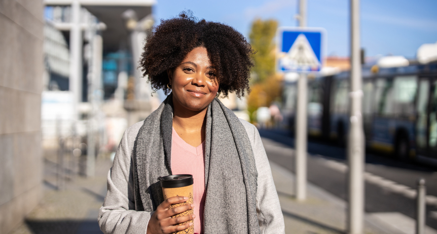woman standing outside smiling with coffee