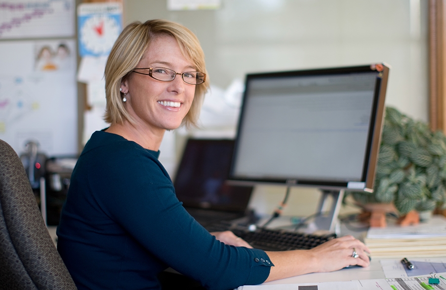 smiling teacher using a computer