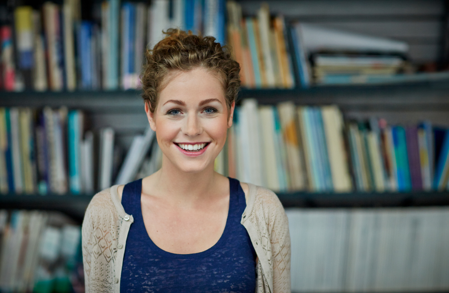 woman smiling in front of shelf of books