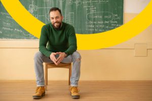 Substitute teacher sitting in front of chalkboard