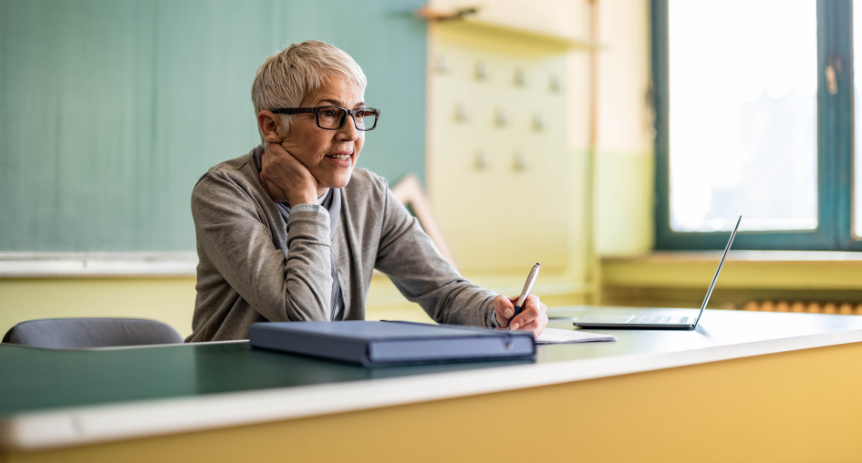 gray haired woman looking stressed at a desk